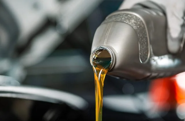 partial view of mechanic pouring motor oil from bottle
